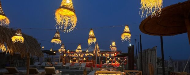 Elegant dinner setup under the stars in Agafay Desert with lanterns and traditional Moroccan decor.