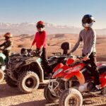 A rider on a quad bike speeding through the golden dunes of the Agafay Desert near Marrakech, with breathtaking rocky landscapes in the background.