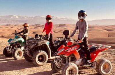 A rider on a quad bike speeding through the golden dunes of the Agafay Desert near Marrakech, with breathtaking rocky landscapes in the background.