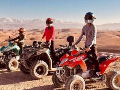 A rider on a quad bike speeding through the golden dunes of the Agafay Desert near Marrakech, with breathtaking rocky landscapes in the background.