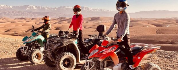 A rider on a quad bike speeding through the golden dunes of the Agafay Desert near Marrakech, with breathtaking rocky landscapes in the background.